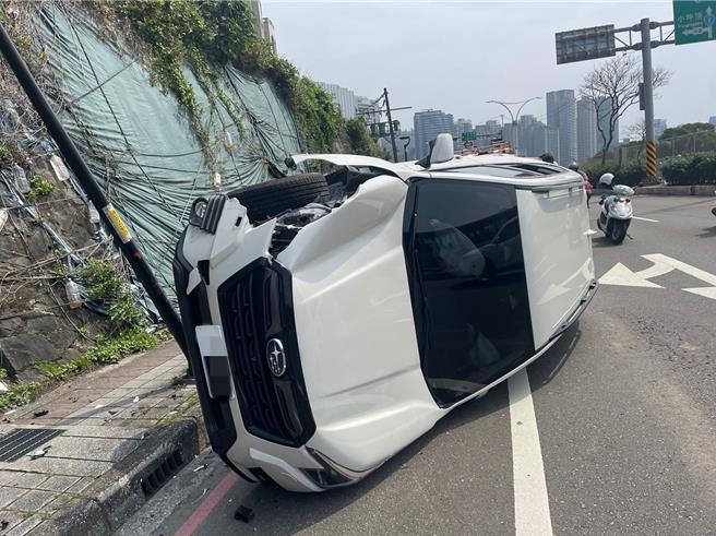 1台白色休旅车自撞路旁路灯座后侧翻。（淡水警分局提供／张铠乙新北传真）