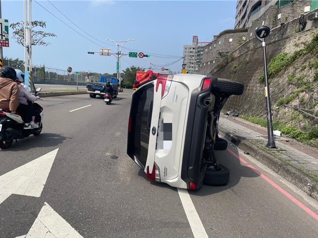 1台白色休旅车自撞路旁路灯座后侧翻。（淡水警分局提供／张铠乙新北传真）