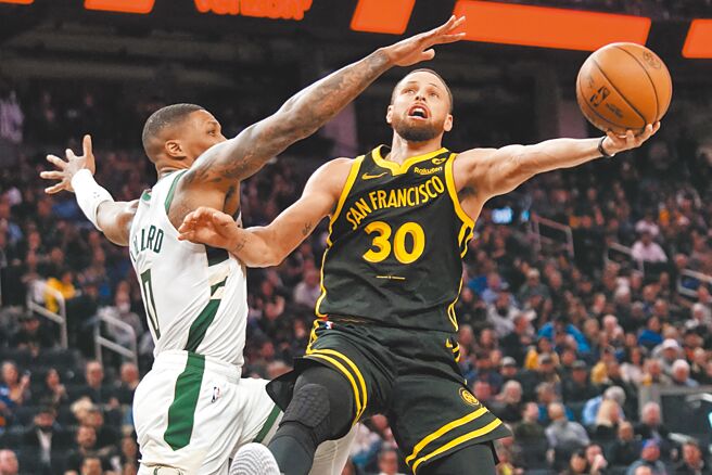 勇士射手柯瑞（右）甩開公鹿控衛利拉德，以左手挑籃得分。（路透）