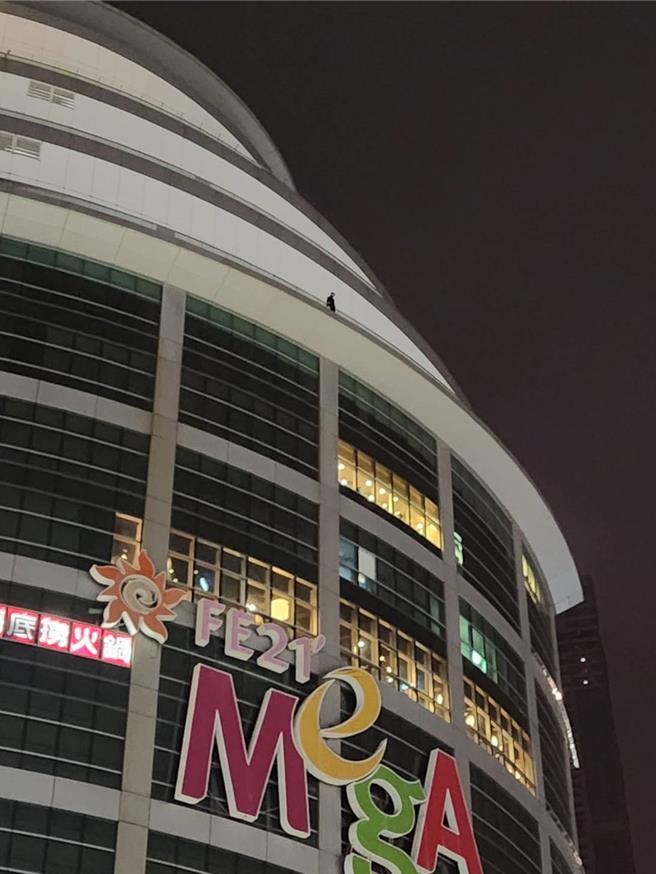 男子站于大远百13楼围墙边让路人惊吓，警消到场与男子沟通1个多小时后成功救出。（任义宇摄）