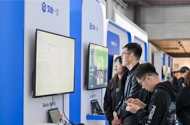 大陆民眾在展区试用百度开发的大模型「文心一言」。（摘自新华社）