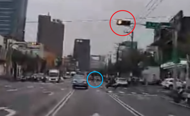 叶姓驾驶开车闯红灯后，还差点撞到走在行人穿越道的民眾（蓝圈处）。（翻摄画面）