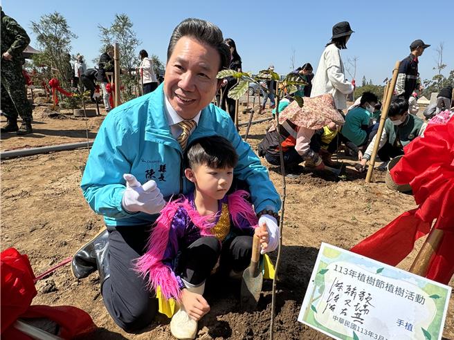 金门县长陈福海与正就读于开瑄国小的孙子携手种下树苗，向民眾传达绿化的观念。(于家麒摄)