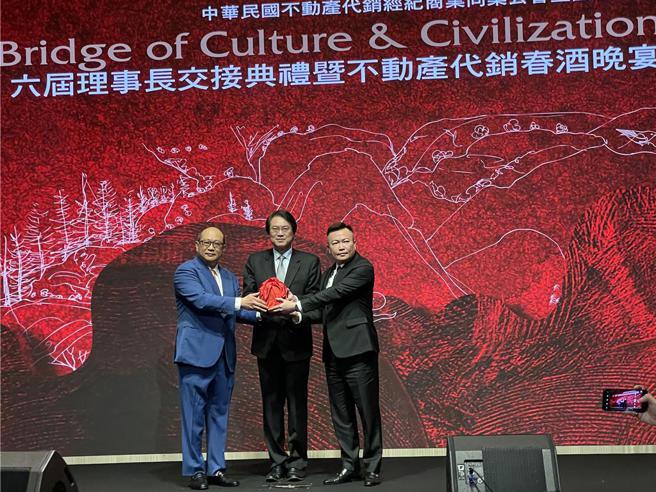 中華民國不動產代銷公會理事長改選，高雄龍登建築機構董事長戴嘉聖（右）接掌龍頭寶座，現任理事長謝坤成將印信自（左）監交人內政部長林右昌（中）手中，移交給戴嘉聖。圖／蔡惠芳