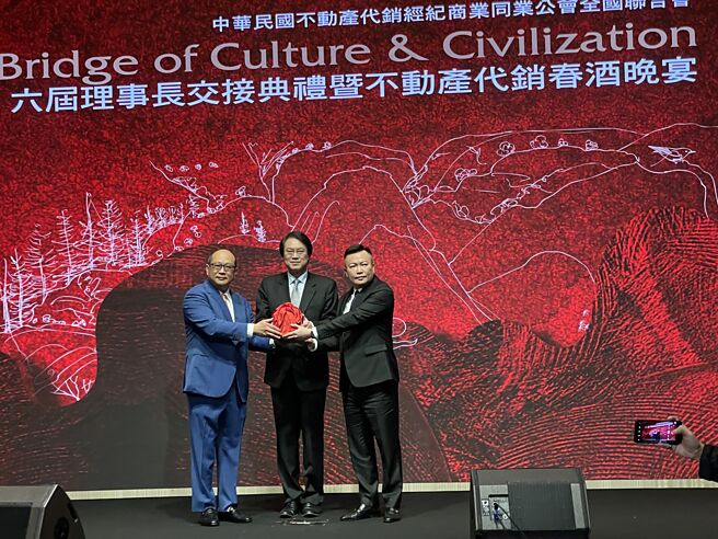 中华民国不动产代销公会理事长15日完成改选，高雄龙登建筑机构董事长戴嘉圣（右）接掌龙头宝座，现任理事长谢坤成（左）将印信自监交人内政部长林右昌（中）手中，移交给戴嘉圣。图／蔡惠芳