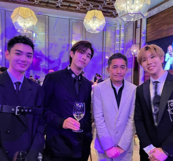 梁朝偉在活動上與男團P1X3L合照，尷尬神情和緊張小手全被拍。（圖／摘自東網）