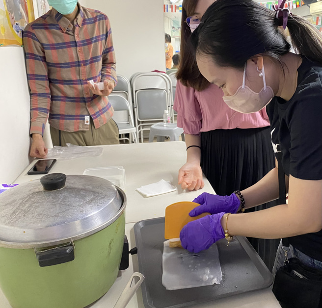 越南新住民翠玉尝试将刚出炉的肠粉包裹油条。(戴志扬翻摄)