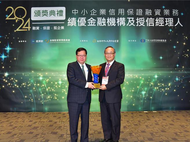 行政院副院长郑文灿（左）颁发信保基金奖项予臺湾企银总经理张志坚。图／臺湾企银提供