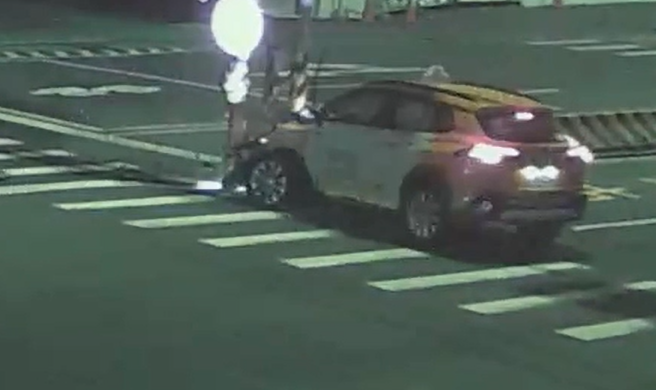 計程車撞上路邊號志燈桿後直接彈起，車頭嚴重毀損。（圖 / 劉詠韻翻攝）