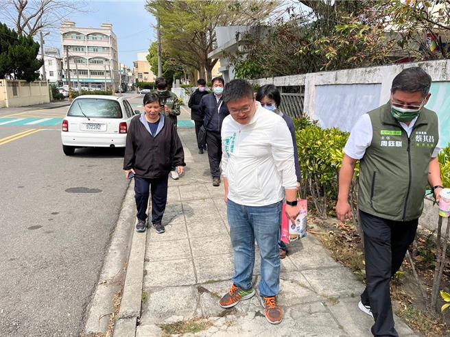 市議員施志昌（前）表示，大甲華龍國小周邊人行道破損不平，且布滿電線竿與電箱，人行道狹窄難行，多年來許多家長不斷反映希望能改善人行道。（讀者提供／張妍溱台中傳真）