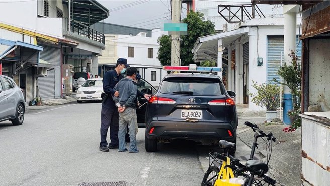 伤人的巫姓男子双手上铐，坐上警车返所归案。（萧嘉蕙摄）