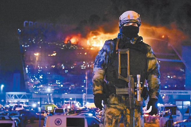 俄國莫斯科近郊的克洛庫斯音樂廳於當地時間22日晚上發生恐怖攻擊事件，造成上百人死傷。圖為音樂廳因遇襲而發生大火，一名俄國國民警衛隊員在現場警戒。（美聯社）