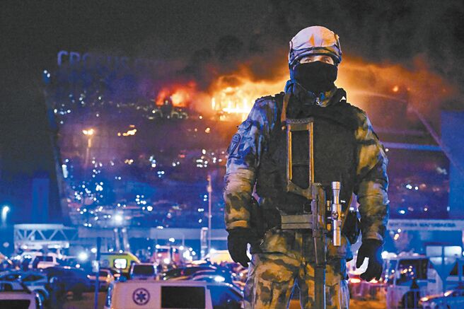 俄国莫斯科近郊的番红花城市大厅音乐厅于当地时间22日晚上发生恐怖攻击事件，造成至少133人死亡，上百人受伤。图为音乐厅因遇袭而发生大火，一名国民警卫队员在现场警戒。（美联社）