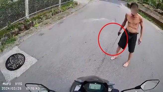 张男持开山刀在马路上拦车，骑士发现立即回头离去。（翻摄画面）