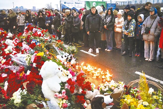 群眾23日聚集在俄羅斯莫斯科西部市郊的番紅花音樂廳旁獻花和點燃蠟燭，莫斯科音樂廳攻擊事件的死亡人數已升至137人。（美聯社）