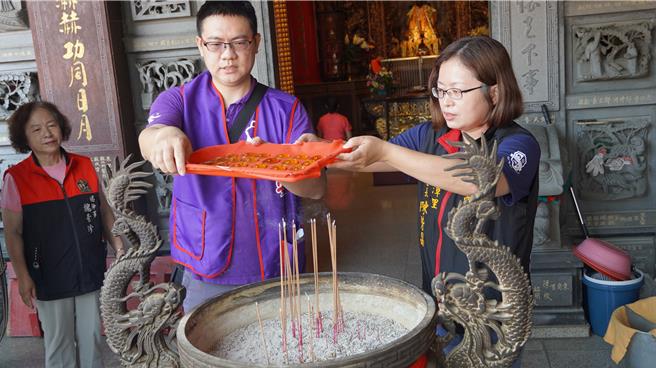 人安善化平安站站長黃坤吉（左）與蓮潭里長陳紫晶（右）共持觀音琉璃玉佩進行過火儀式。（寶智華攝）