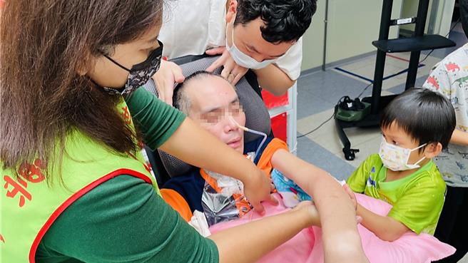 年仅6岁的高小弟帮植物人爸爸阿福擦拭手臂。（萧嘉蕙摄）