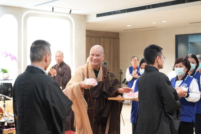 繫念和尚悟道法师发放寿桃，大家同庆观世音圣诞祝福。(戴志扬翻摄)