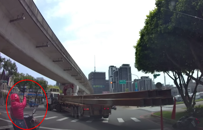 等红灯骑士被K头后，赶紧弃车逃到分隔到上，但没想到1名大妈骑士，看得被K头骑士没事，竟挥手指挥疑似要拖板车司机开离。（图／ 翻摄自「WoWtchout-地图型行车影像分享平台」）