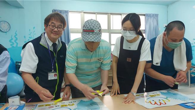 台电高雄区处处长张以诺(左一)与中心的星星儿一起完成电宝创意贴的活动。（台电提供）