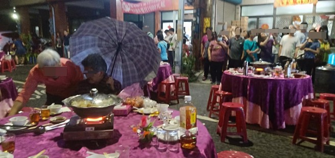 阿嬤淡定打起傘繼續吃流水席。（圖／羅來福提供）