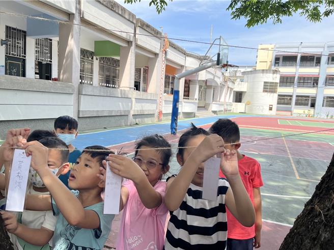 儿童节将至，屏东县林边乡仁和国小2日让孩子们写许愿卡挂在树龄55年的校树印度紫檀，为学童送上希望与幸福。（谢佳潾摄）