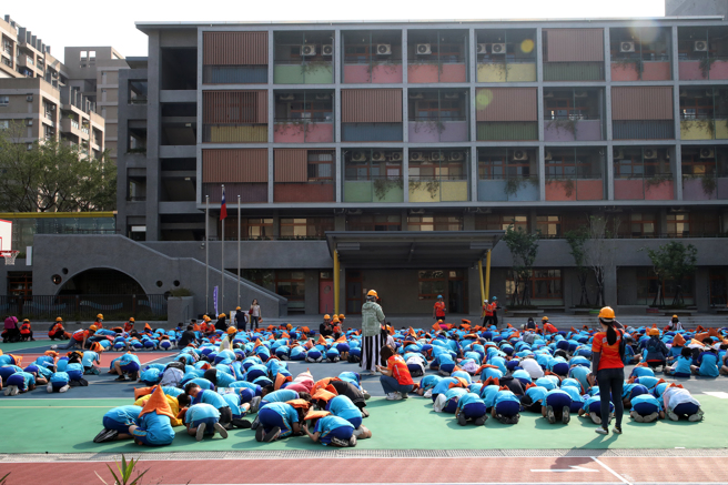 台北市新和國小全校師生立即疏散到操場，由於餘震不斷，同學們也立即保護頭頸就地掩護。（劉宗龍攝）