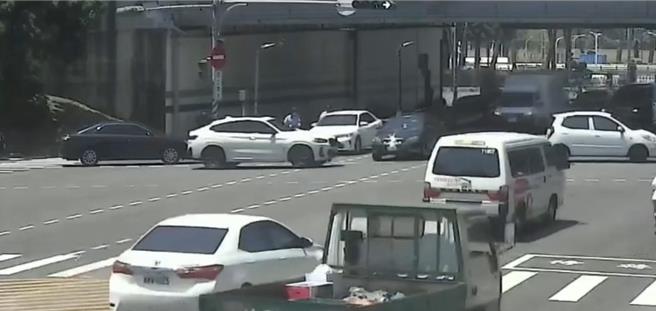 一輛白色BMW休旅車疑似想闖紅燈，遭綠燈直行黑色轎車阻擋，竟惱羞成怒追上前持棍棒攔車。（警方提供／任義宇高雄傳真）