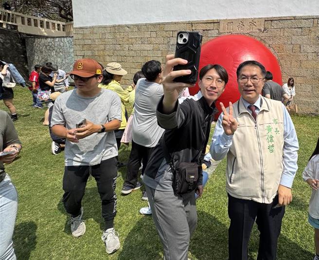 民眾爭相拉著黃偉哲一起跟紅球合影。（曹婷婷攝）