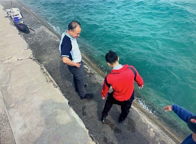 2024年4月10日澎湖縣／澎湖西嶼合界碼頭一名釣客6日耍帥拍照不慎落海，碼頭斜坡過陡又有浪爬不上來，竹灣派出所所長林輝雄（左）獲報後趕往，利用現地漁船用纜解下一段來將釣客（紅衣者）套住救起。（警方提供／許逸民澎湖傳真）