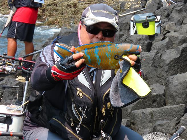 85矶钓好手，13日在澎湖无人岛扬竿竞赛，钓起鱼获的选手喜不自胜展示战利品。（许逸民摄）