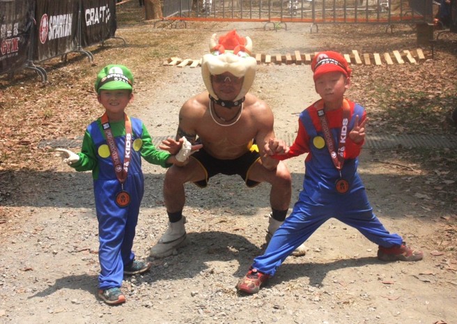 斯巴达障碍赛代言人林均澔（中）开心带着两名儿子完赛2024斯巴达障碍赛高雄站小勇士组别，父子3人还特地扮成电玩超级玛利欧兄弟里的角色。（大会提供）