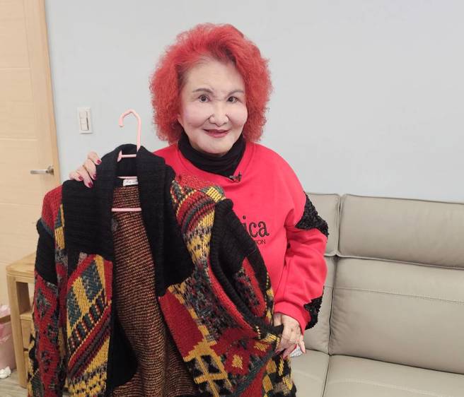 陈今佩开心介绍母亲遗留下来的针织大衣。(游定刚拍摄)