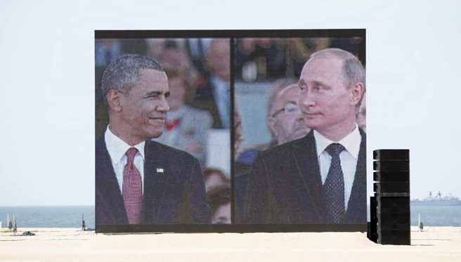 2014年6月6日，宝剑海滩上的巨大视讯萤幕显示美国总统欧巴马和俄罗斯总统普丁参加国际诺曼第登陆 70 周年纪念仪式。（路透社)