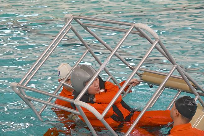 國防部17日在岡山國軍空勤人員求生訓練中心舉行模擬水中事故演練，圖為人員模擬在艙內解開安全帶後的逃生情形。（林瑞益攝）