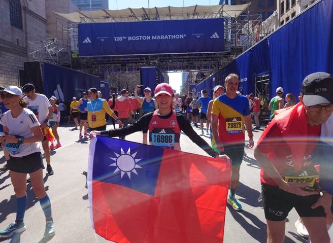 跑齡僅4年的王妍蓉，首度參加波士頓馬拉松，披著國旗通過終點，接受歡呼。（讀者提供）