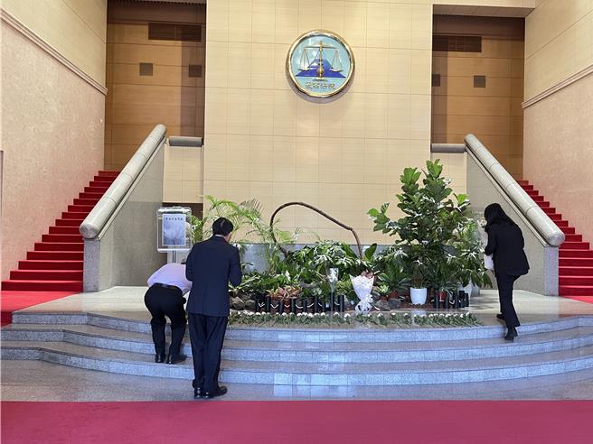 最高法院19日在一樓大庭設追悼區，並在盆栽上繫上白絲帶，法官們陸續獻花表達思念。（林偉信攝）