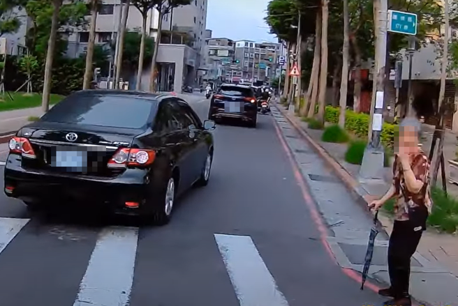 一名阿嬷要过马路，由于往来车辆许多，吓得她不敢往前走。（图／ 翻摄自「WoWtchout-地图型行车影像分享平台」）