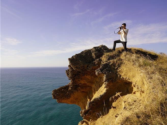 林鉦翔站在紐西蘭海邊懸崖取景，得小心突如其來的強風。（林鉦翔提供／孫英哲彰化傳真）