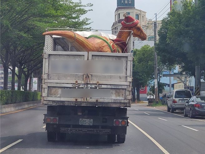日前斗六市街头出现一部资源回收车载戴耶诞帽的恐龙逛街，资源回收车来自北港镇，令人好奇去处。（周丽兰摄）