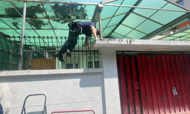 员警赖丁嘉爬上梯子后，从大门旁翻墙跨越栏杆进入屋内，顺利地将阳台铁门打开成功解救。 （翻摄画面）