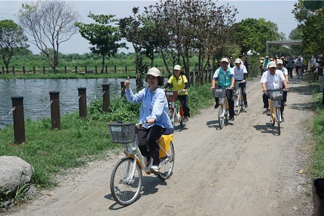 屏东县长周春米（左一）在风景优美的海丰溼地生态池骑单车，响应世界地球日。（罗琦文摄）