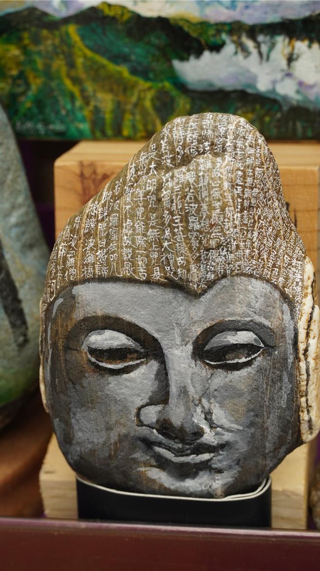 陈宝清将石头彩绘成佛像，佛头以小楷抄写心经。（宝智华摄）