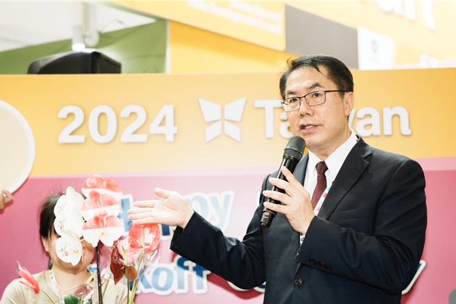 台南市长黄伟哲率队赴新加坡食品展，在台上介绍喷印台南市徽及新加坡国徽的后壁兰花，以及闻名全台的六甲火鹤花。（台南市政府提供／张毓翎台南传真）