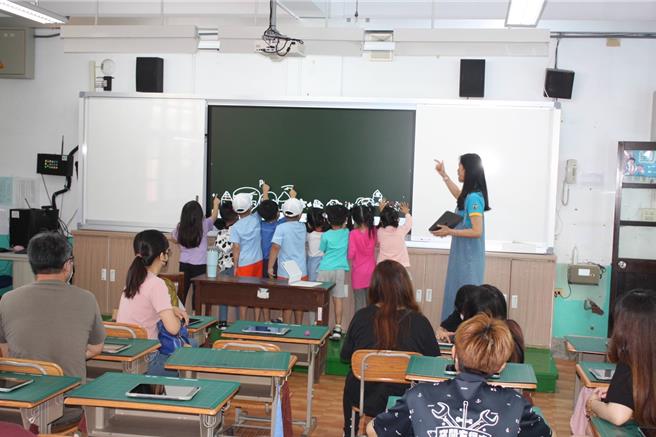 斗六市镇东国小在小一新生报到日邀请家长进入班级观课，体验数位学习的先进，小朋友站到黑板上围着老师学习，在台下听讲的都是家长。（镇东国小提供）