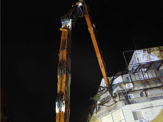 花莲市富凯大饭店昨因密集地震倾斜倒塌，工程单位今天傍晚完成8米填土工作，稳定建物基础，全国最长长达42米的大割机「鲁夫号」晚间8时45分正式开拆，力拚2周拆完。（罗亦晽摄）