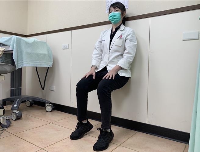 第二式「深蹲垫脚站立」，站姿，身体贴墙，双脚踩稳后深蹲至大腿与地面平行，垫起脚尖停留10至15秒，再站直。1组15下，训练小腿肌力。（高市活力得中山脊椎外科医院提供／杨舒婷高雄传真）