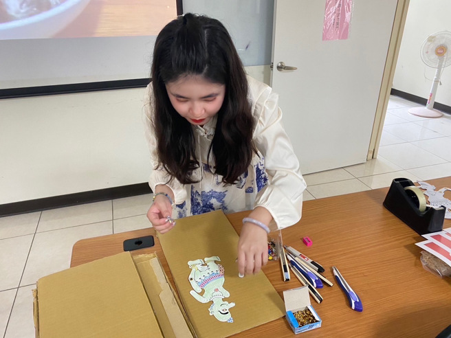 讲师蔡佳伸以双脚钉连接皮影人偶的关节，以便后续操作皮影人偶。(移民署嘉义市服务站提供)