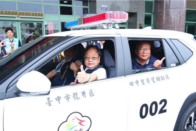 台中市龙井区田中里守望相助队今年2月助警方追捕逃逸车辆，遭对方衝撞致车头严重损毁。市府与里队筹措72.2万元添购巡逻车，26日于龙井区公所前广场举办交车典礼，民政局长吴世伟等人（左）体验新车装备。（中市府提供／潘虹恩台中传真）
