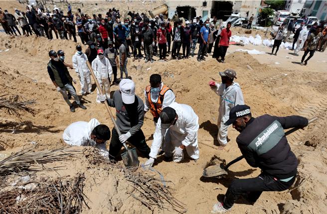 在迦薩走廊南部汗尤尼斯，迦薩人正努力將埋葬在納瑟醫院的巴人屍體搬入墓地。（路透社）